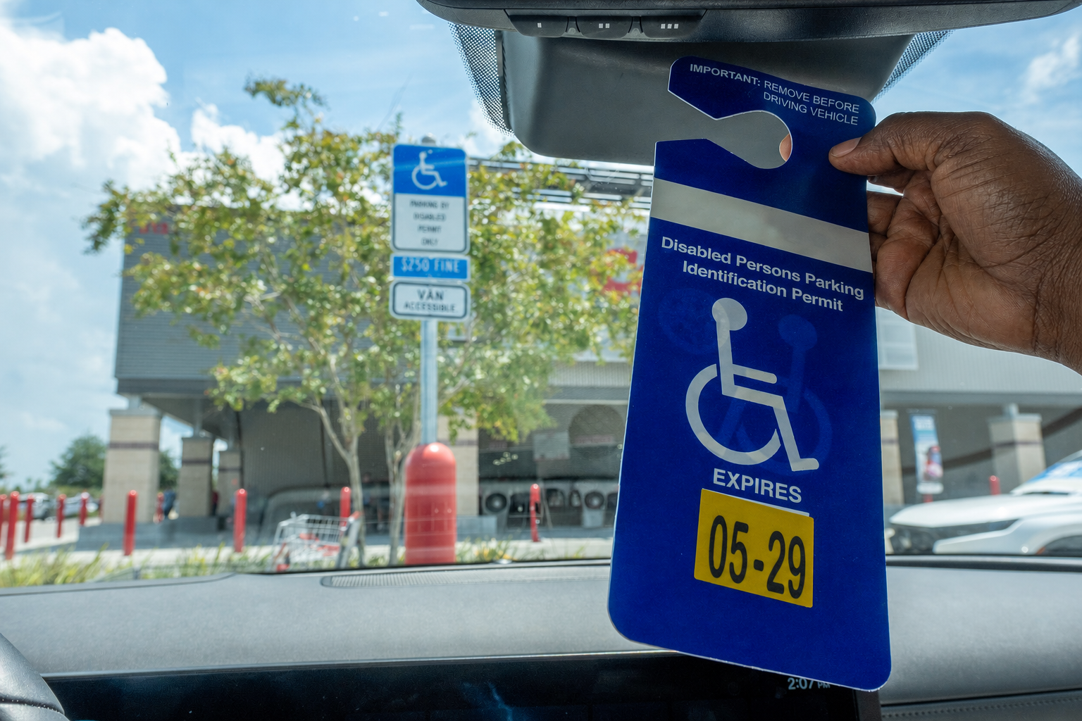 Hand holding a disabled persons parking identification permit in a car